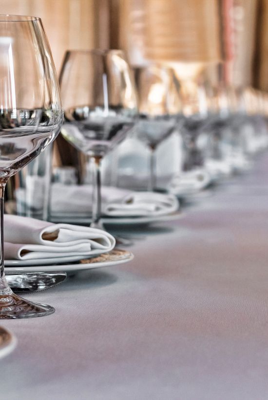 A table is elegantly set with wine glasses, plates, and neatly folded napkins, suggesting a formal dining setup.