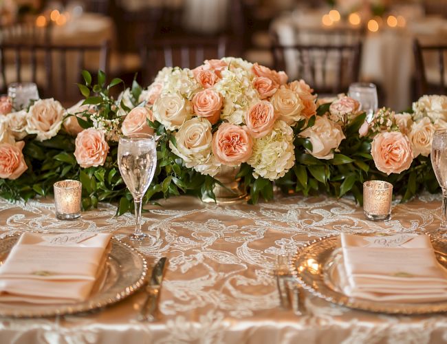 A beautifully decorated table with floral centerpieces, elegant place settings, and candles, perfect for a formal event or wedding reception.