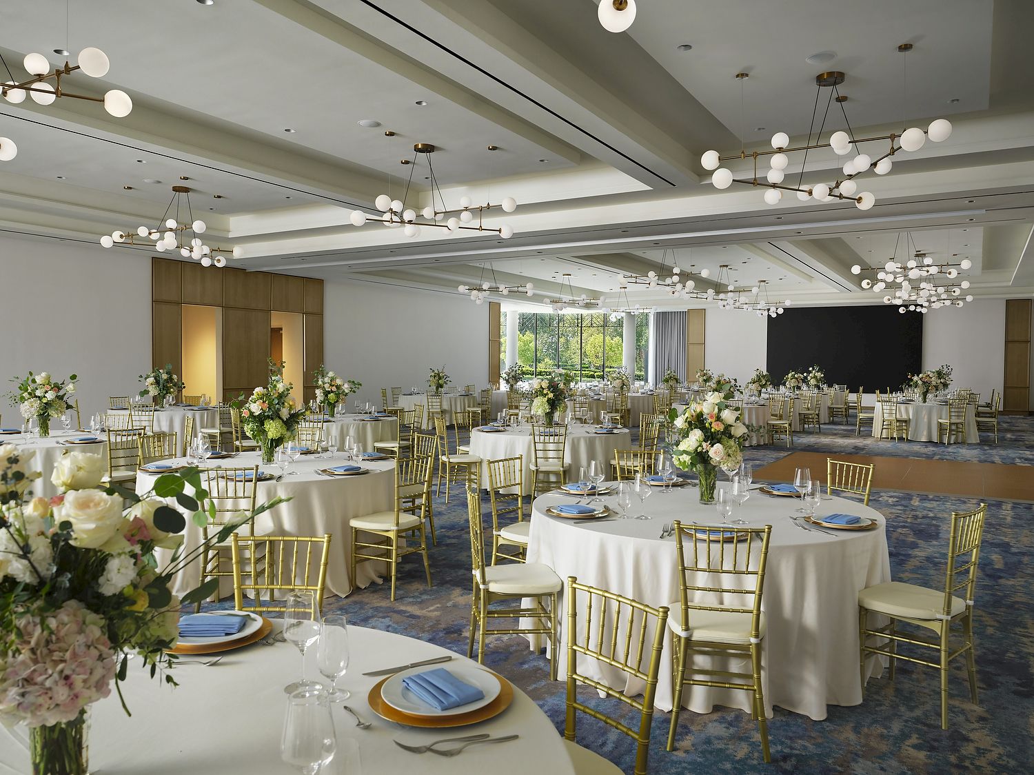 Ballroom at Hilton Arcadia Pasadena Area set for a wedding reception with round tables, gold chairs and white floral centerpieces