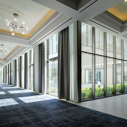 Sunlit ballroom prefunction space at Hilton Arcadia Pasadena Area with floor-to-ceiling windows
