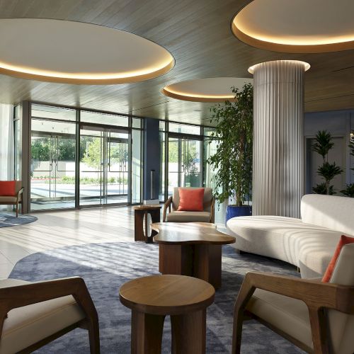 Bright hotel lobby at Hilton Arcadia Pasadena Area with curved sofas, lounge chairs and floor-to-ceiling windows